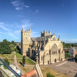 A large cathedral with a tall spire stands in the middle of a city.