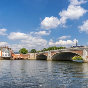 A bridge over a body of water with a building on the left.