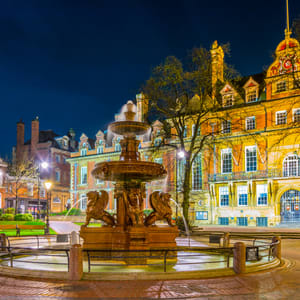 A fountain in front of a building with a clock tower.