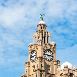 A large clock tower with a green statue on top.