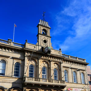 A large building with a clock tower and a flag on top.