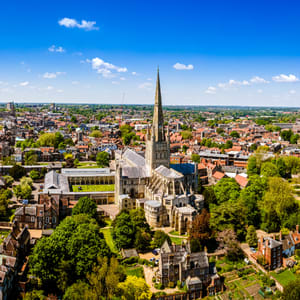 A church with a tall spire is the focal point of a cityscape.
