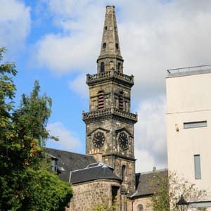 A church steeple with a clock is in front of a white building.