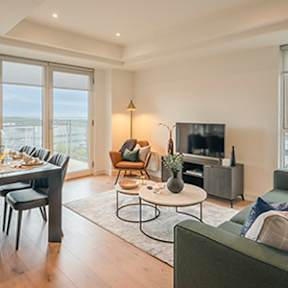 A living room with a grey couch, a coffee table, a dining table, and a television at Cherrywood Apartments, D18 VY3V, DUBLIN 18