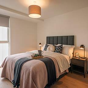 A bed with a pink blanket and pillows is in a room with a lamp on a side table at Cherrywood Apartments, D18 VY3V, DUBLIN 18
