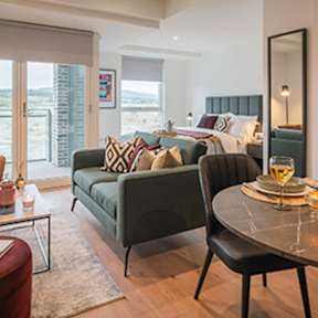 A living room with a green couch and a round table at Cherrywood Apartments, D18 VY3V, DUBLIN 18