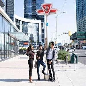 three people standing on a sidewalk next to a street sign