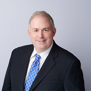 A man in a black suit and blue tie.