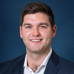 a young man wearing a suit and a blue background