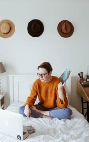 a woman sitting on a bed reading a book