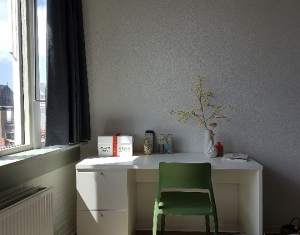 A white desk with a green chair and a white container on it.