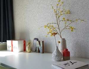 A white desk with a green chair and a vase with yellow flowers.