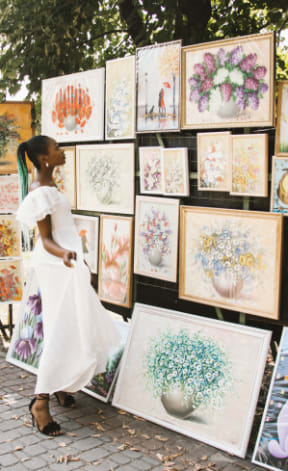 a woman in a white dress standing in front of a wall of paintings