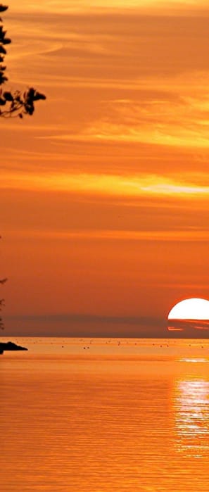 the sun sets over the ocean at the beach