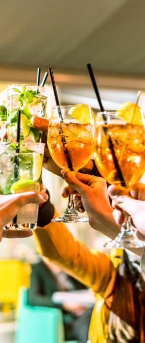 people holding up cocktails at a bar