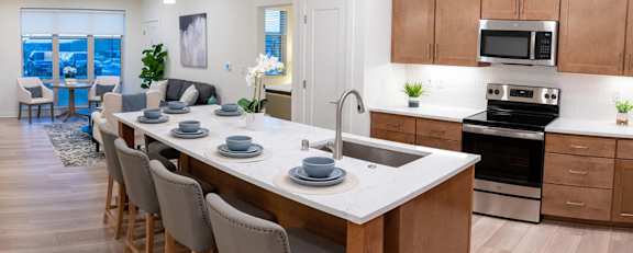 an open kitchen and living room with a large island with plates on it