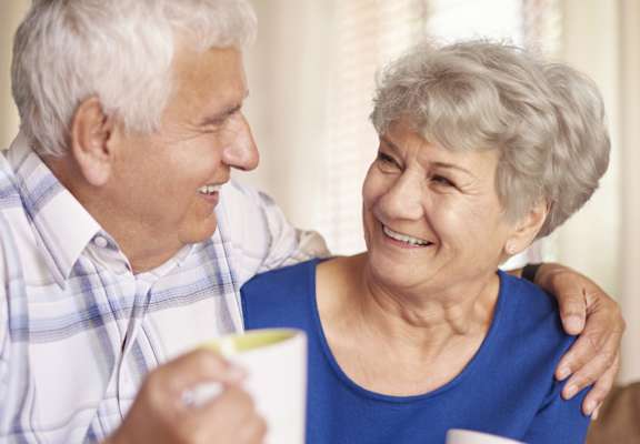 a man and a woman sitting on a couch looking at each other and smiling
