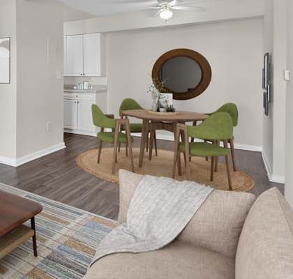 A living room with a brown sofa, a wooden coffee table, and a round mirror on the wall.