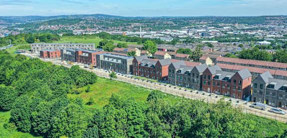 A large building complex with a green hillside in the foreground.