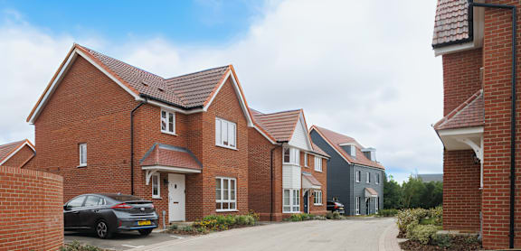 A row of houses with a car parked in front of the first one.