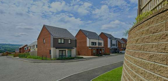 A row of houses with a brick wall on the right.