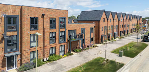 A row of red brick houses with green lawns in front.