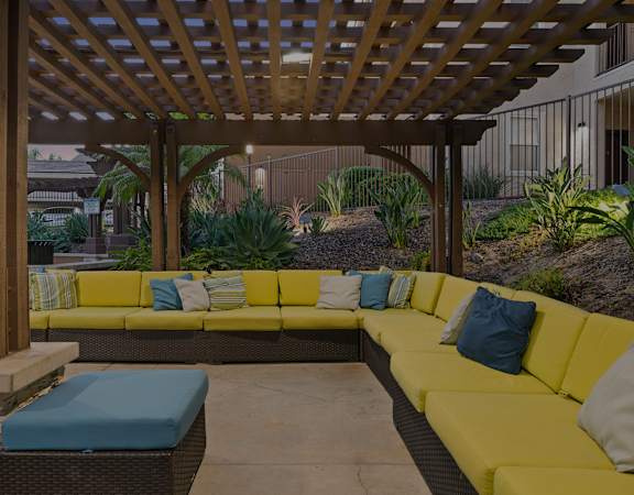a pergola with yellow couches and blue pillows
