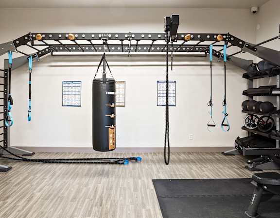 a fitness room with weights and a punching bag on the wall