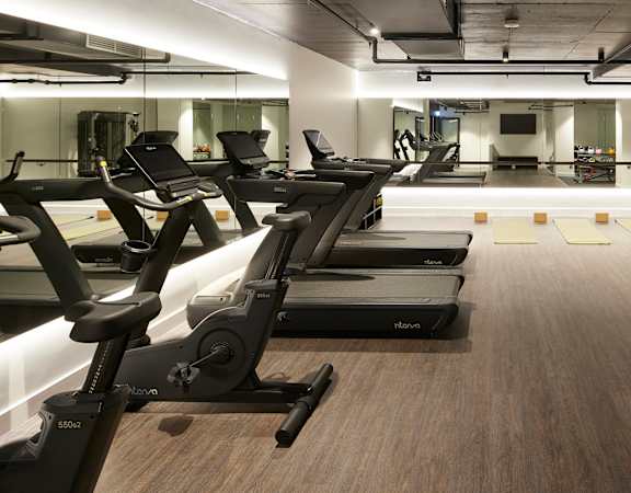 a gym with cardio machines and weights on a wooden floor