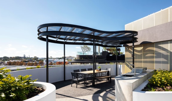 a roof terrace with a table and chairs and a black canopy