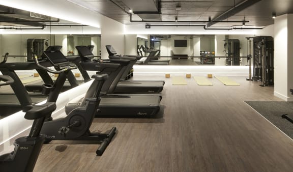 a gym with cardio machines and weights on a wooden floor