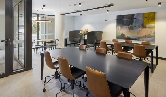 a conference room with a table and chairs and a painting on the wall