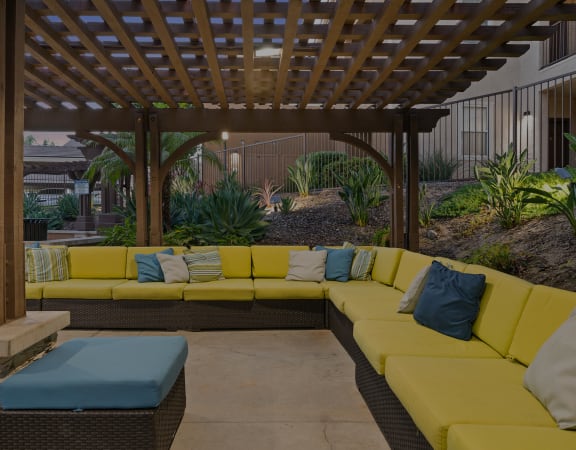 a pergola with yellow couches and blue pillows