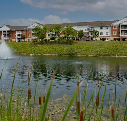 a pond with a fountain in front of an apartment building