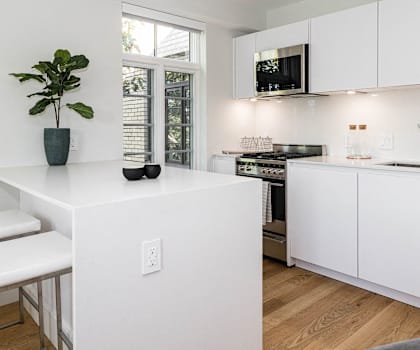 A white kitchen with a stove, sink, and cabinets.