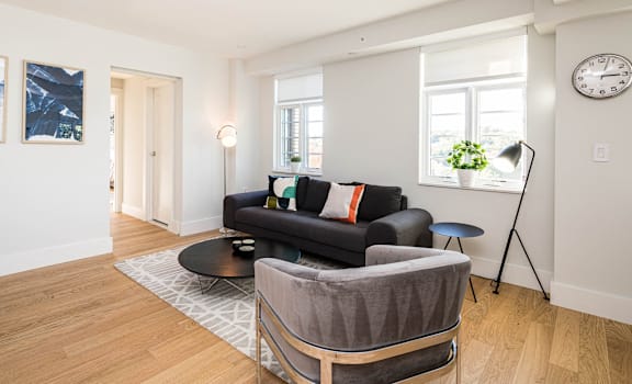 A living room with a black couch and a grey chair.
