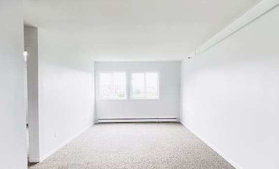 A room with a carpeted floor and a window.