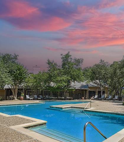 a swimming pool at a resort with trees and a pink sky