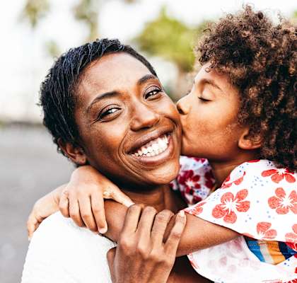 A woman is hugging a child from behind.