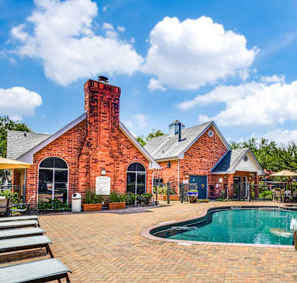 a swimming pool in front of a brick house clubhouse