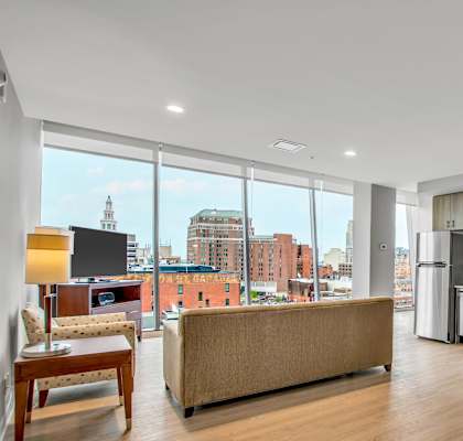 A living room with a couch, chairs, and a view of the city.