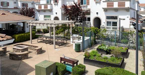 A courtyard with a bench, a table, and a fence.