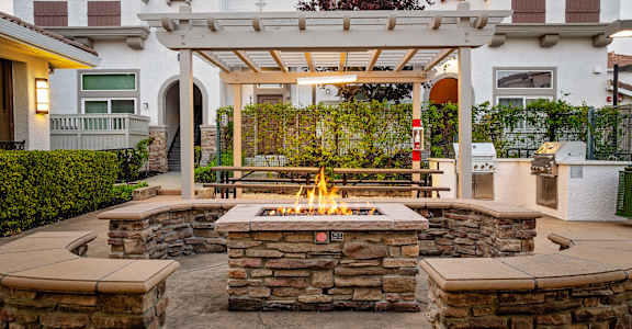 A patio with a fire pit and a pergola.