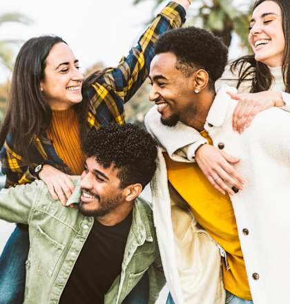A group of friends are hugging and laughing together in an outdoor setting.