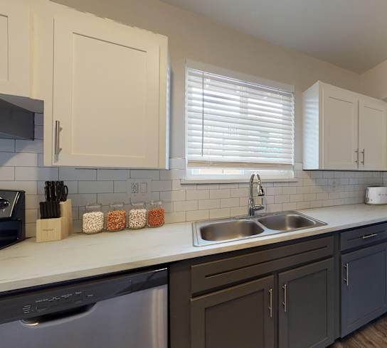 A modern kitchen with a stainless steel refrigerator, sink, and cabinets.