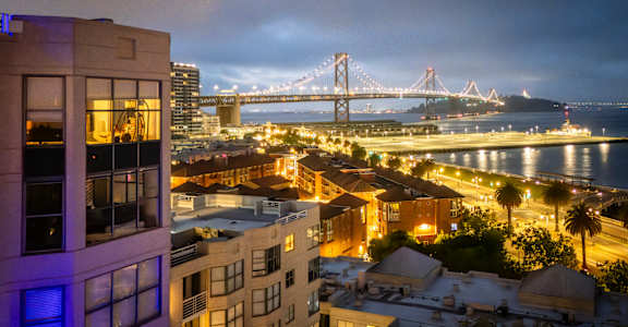 A cityscape at night with a bridge in the background.