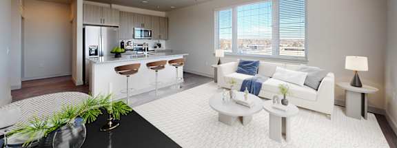 A modern living room with a kitchen area in the background. at Railside at Wadsworth Station, Colorado
