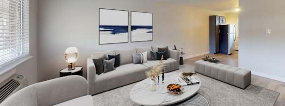 A modern living room with a grey sofa, a white coffee table, and a painting on the wall.