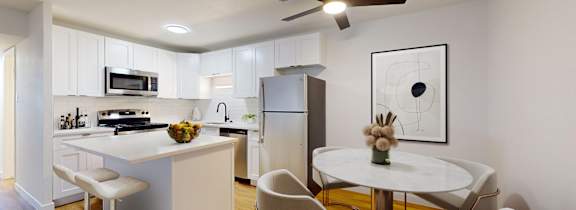 A modern kitchen with a white island and a dining table set for four.