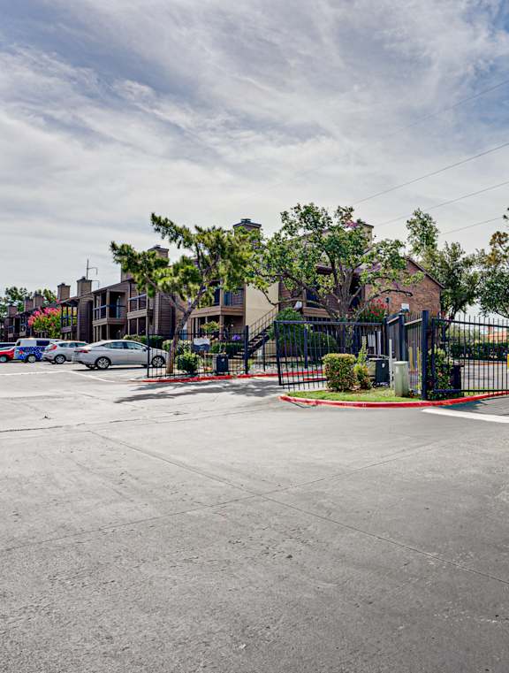A parking lot with a building and trees in the background.